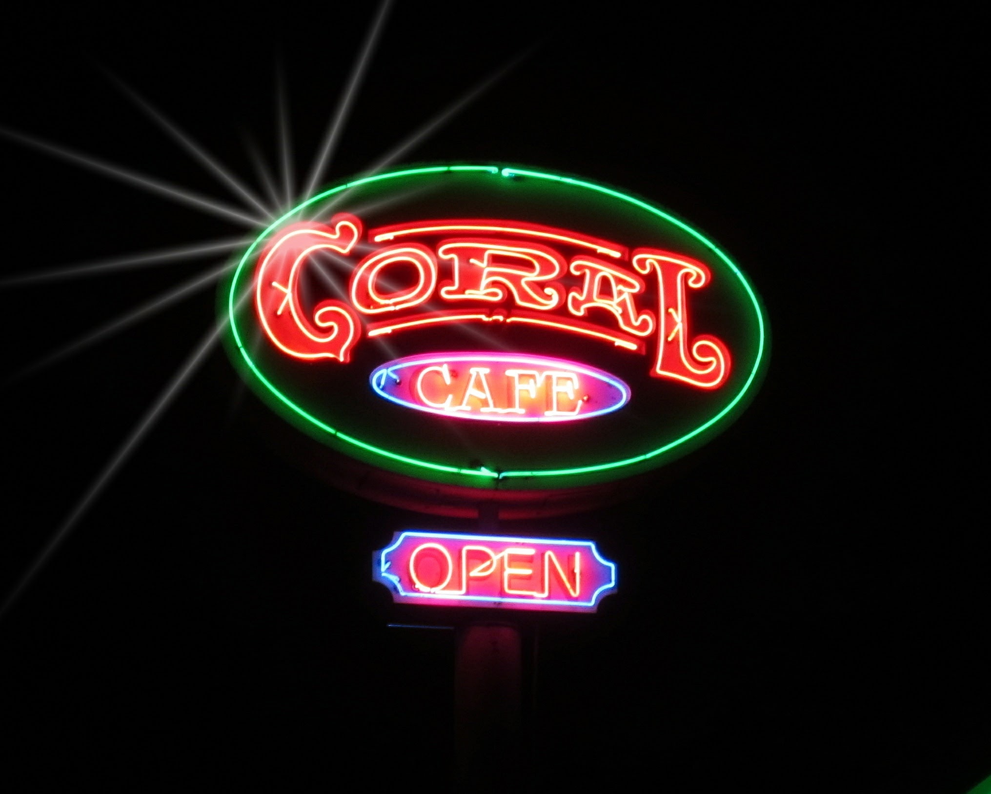 The Coral Cafe neon sign lit up at night